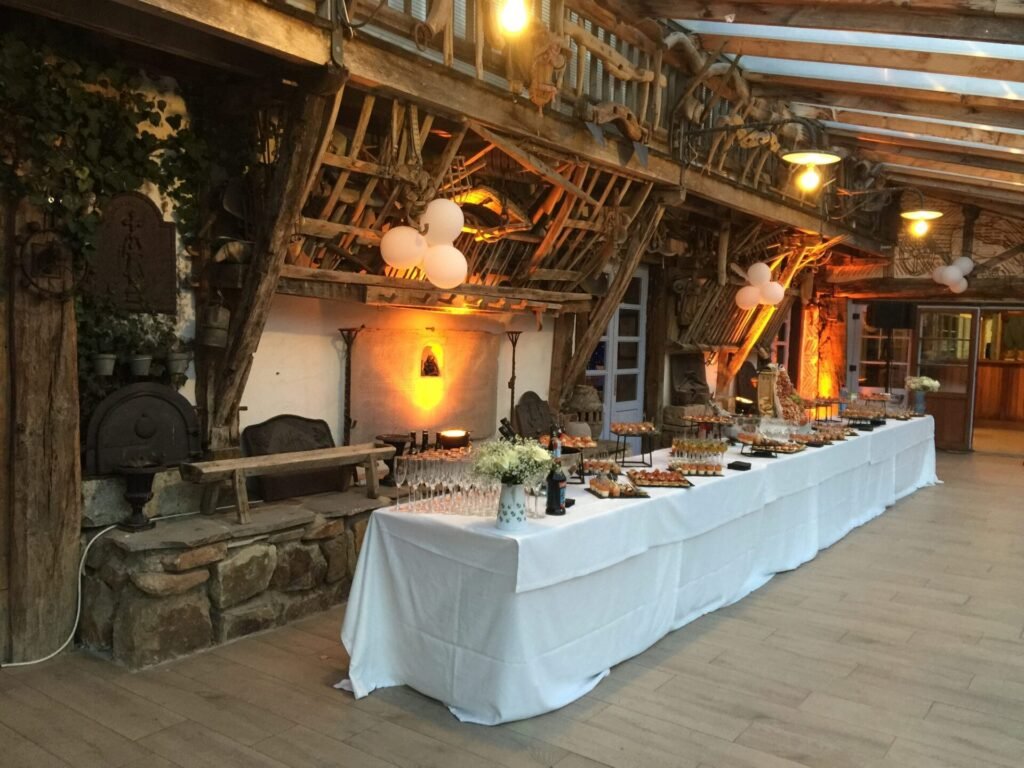 Buffet dressé sous la charpente d’une bergerie éclairée en chaud