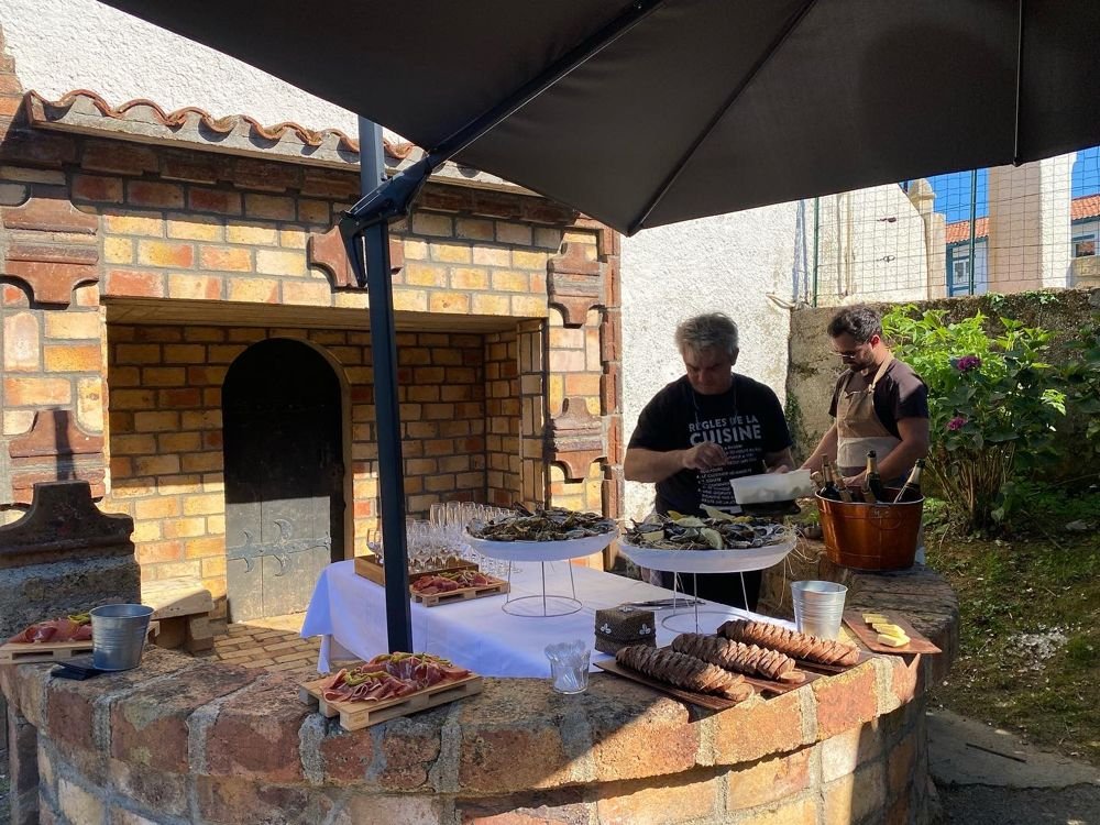 Deux cuisiniers à l’œuvre devant un four à bois, buffet dressé au premier plan