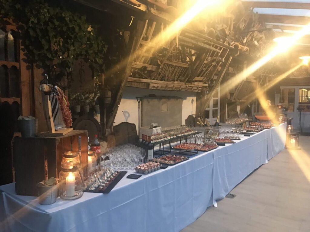 Long buffet dressé dans une bergerie à charpente apparente au soleil couchant